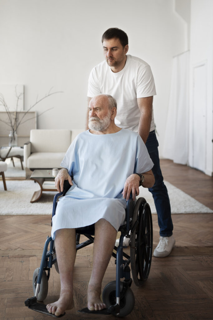Elderly man in a wheelchair being assisted by a male nurse, representing elderly caregiver services in Dubai